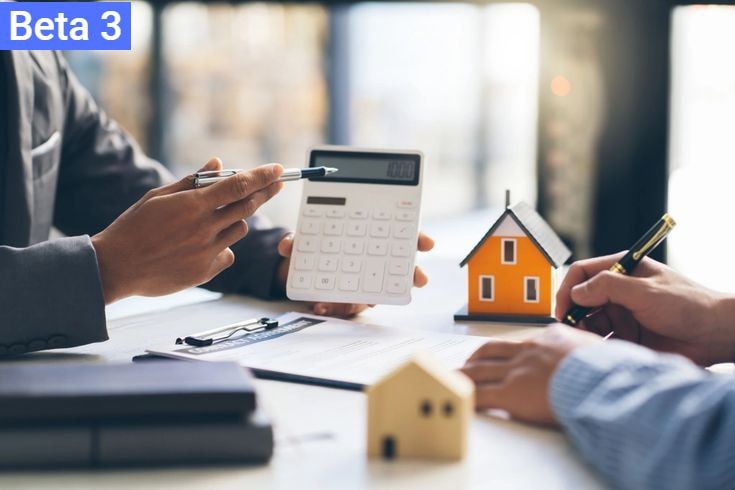 Two individuals discuss financial matters using a calculator with small house models on the table.